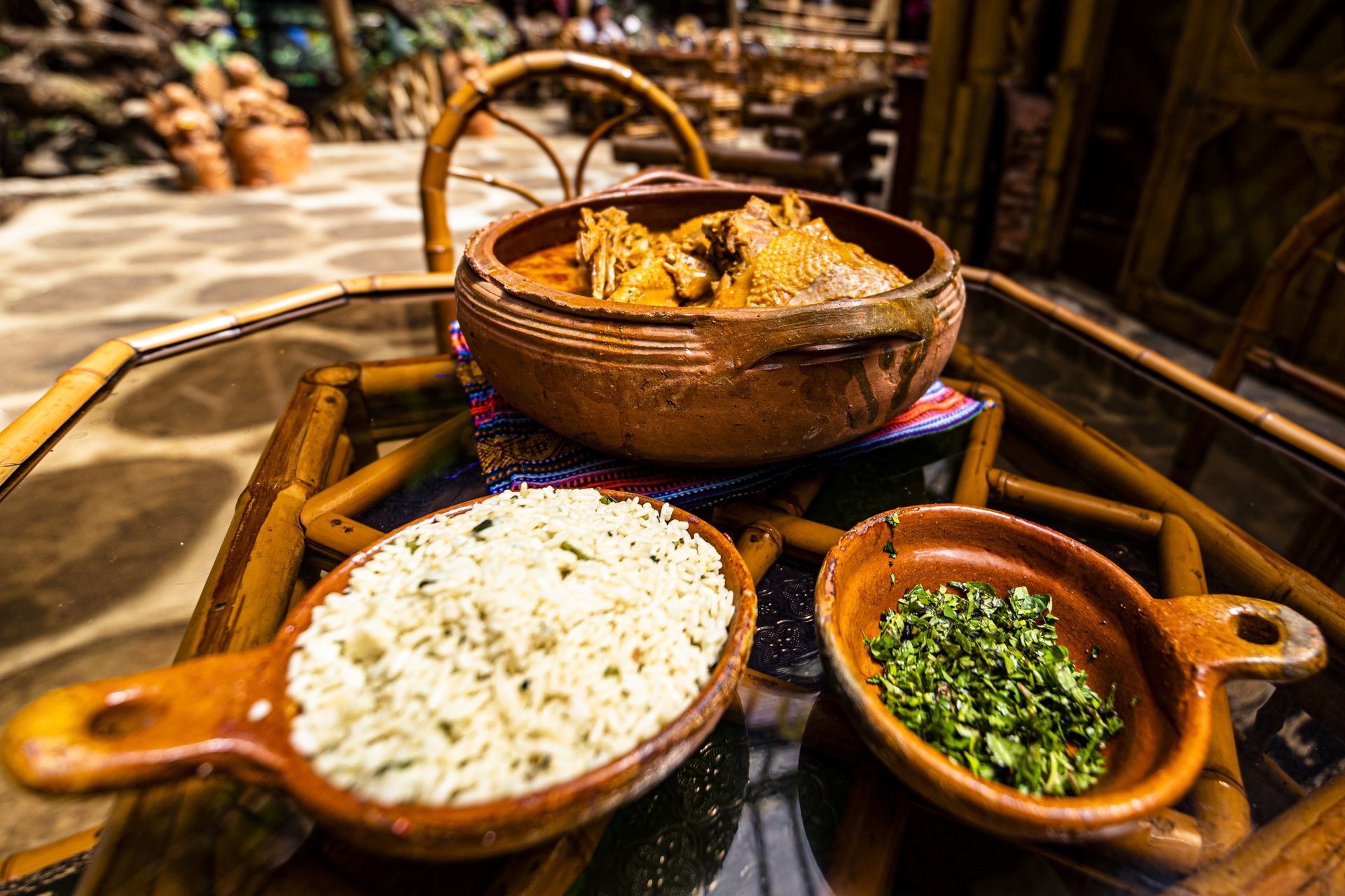 Kaq’ik in a clay pot with rice and green recado on a bamboo table at the Ram Tzul restaurant